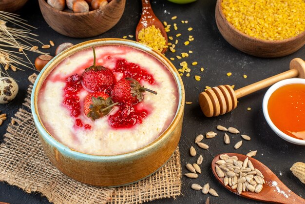 Vue rapprochée d'un délicieux petit déjeuner servi avec de la confiture de fraises dans un bol et des oeufs de noisettes riz jaune sur fond de couleur foncée