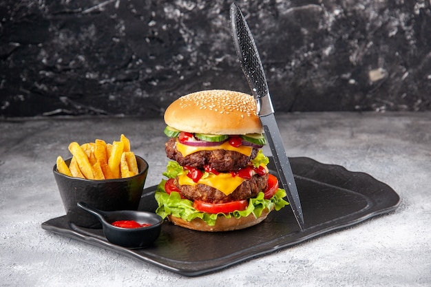 Vue rapprochée d'un délicieux sandwich fait maison et de frites de ketchup à la fourchette vert sur tableau noir sur une surface isolée en détresse grise