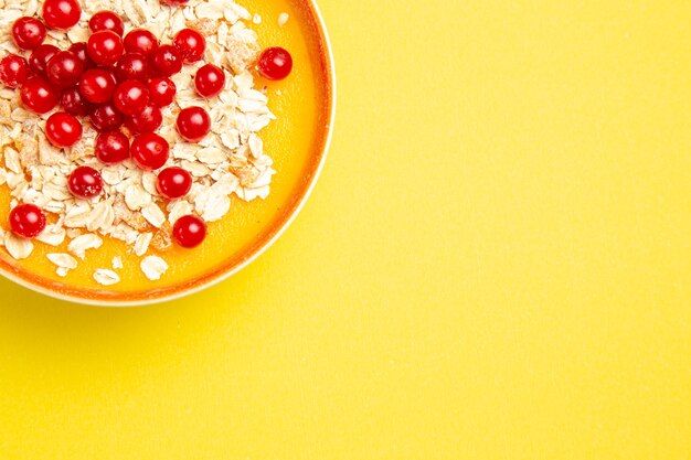 Vue rapprochée de dessus de baies d'avoine de baies rouges dans le bol orange sur la table