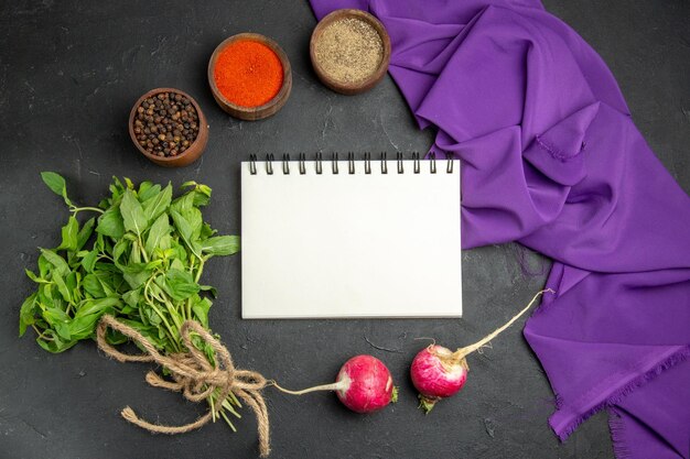 Vue rapprochée de dessus épices cahier blanc radis herbes épices colorées et nappe violette