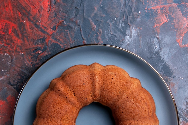 Vue rapprochée de dessus un gâteau appétissant un gâteau sur la plaque ronde bleue sur la table sombre