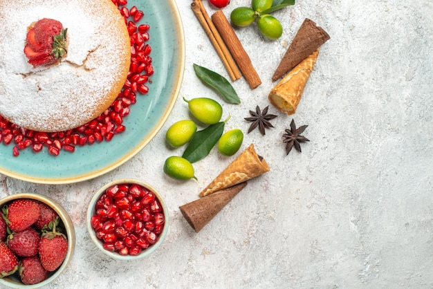 Photo gratuite vue rapprochée de dessus un gâteau un gâteau appétissant bols de baies limes bâtons de cannelle agrumes