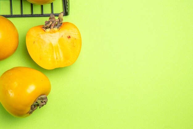 Vue rapprochée de dessus kakis trois kakis à côté du panier gris sur fond vert