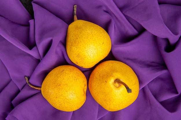 Vue rapprochée de dessus poires sur la nappe trois poires appétissantes sur la nappe violette