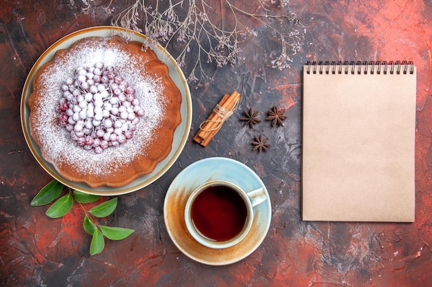 Vue rapprochée de dessus une tasse de thé une tasse de thé anis étoilé un gâteau cahier blanc cannelle