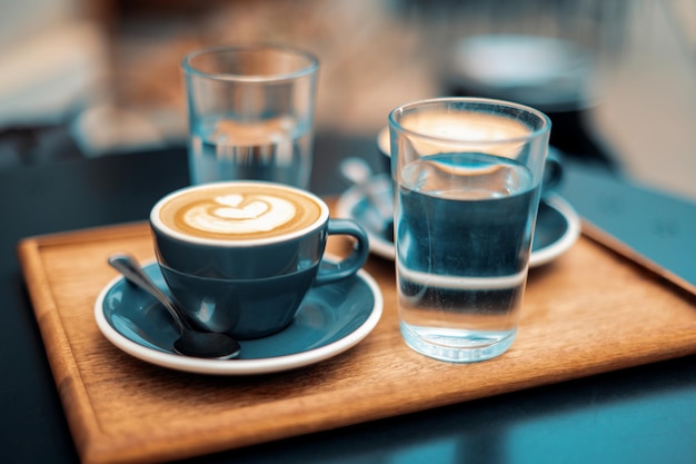 Photo gratuite vue rapprochée de deux tasses de café au lait avec deux tasses d'eau