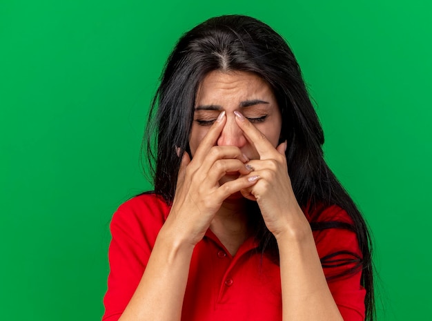 Vue rapprochée de la douleur jeune femme malade mettant les doigts sur le nez avec les yeux fermés isolé sur mur vert avec espace copie