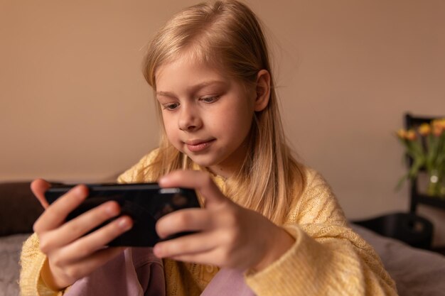 Vue rapprochée d'une drôle de fille regarde le téléphone