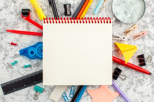 Vue rapprochée du cahier à spirale fermé en spirale et de divers appareils de bureau sur une surface blanche