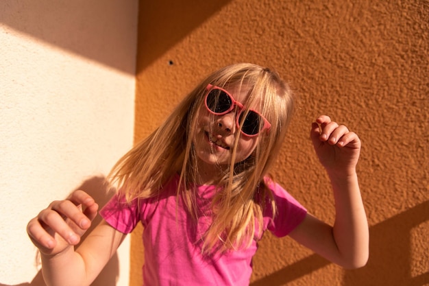 Vue rapprochée du charmant jeune enfant drôle sourire à la caméra en lunettes de soleil