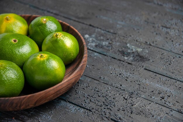 Vue rapprochée du dessus des citrons verts sur la table des citrons verts-jaunes dans un bol sur une table grise