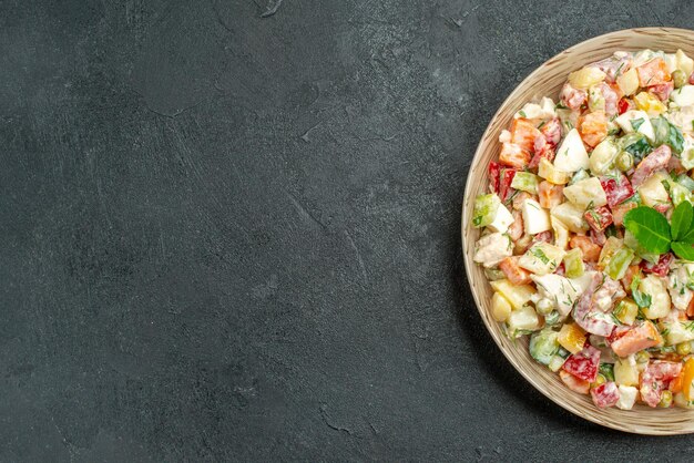 Vue rapprochée du haut du bol de salade de légumes sur le côté droit avec du vert dessus sur fond vert foncé