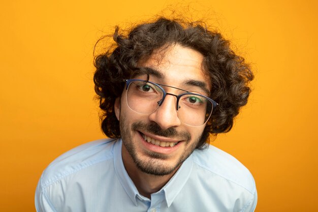 Vue rapprochée du jeune bel homme portant des lunettes regardant avant isolé sur mur orange 89