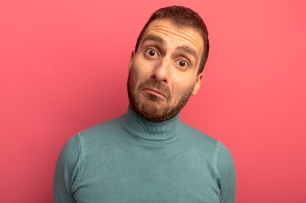 Vue rapprochée du jeune homme surpris regardant avant isolé sur mur rose