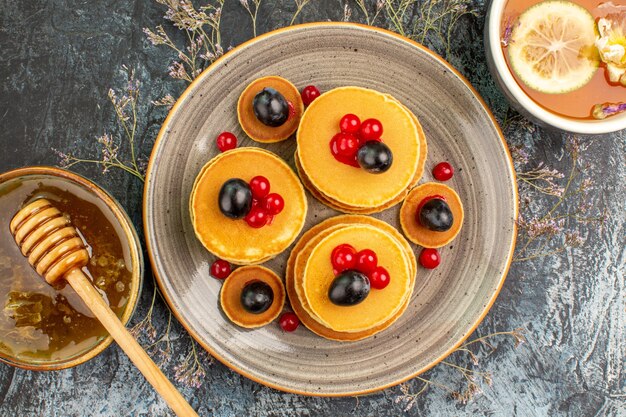 Vue rapprochée du miel de crêpes aux fruits avec une cuillère en bois et une tasse de thé