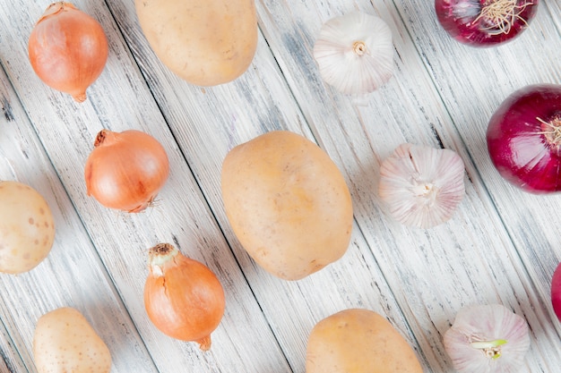 Vue rapprochée du motif de légumes comme la pomme de terre à l'ail oignon sur fond de bois