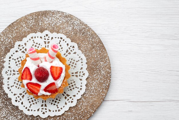 Vue rapprochée du petit gâteau délicieux avec de la crème et des fraises en tranches sur blanc