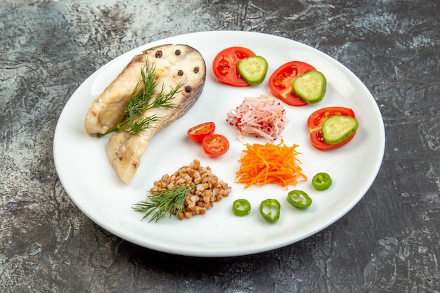 Vue rapprochée du sarrasin bouilli servi avec des légumes verts sur une plaque blanche sur une surface de glace avec espace libre