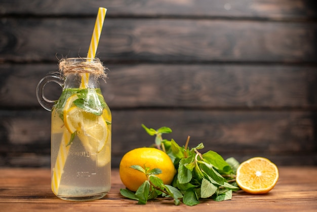 Vue rapprochée de l'eau de désintoxication naturelle fraîche servie avec de la menthe en tube et de l'orange sur fond marron