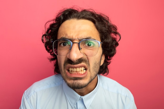 Vue rapprochée de l'ennuyé jeune bel homme portant des lunettes à l'avant isolé sur un mur rose