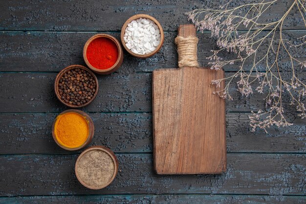 Vue rapprochée des épices et planche à découper entre différentes épices et branches colorées sur la table