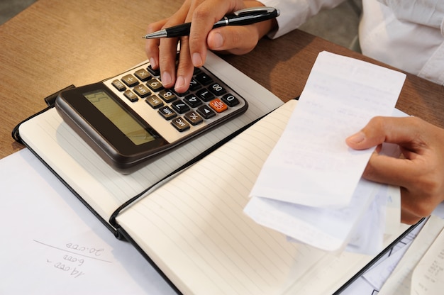 Vue rapprochée d'une femme calculant des factures sur une calculatrice