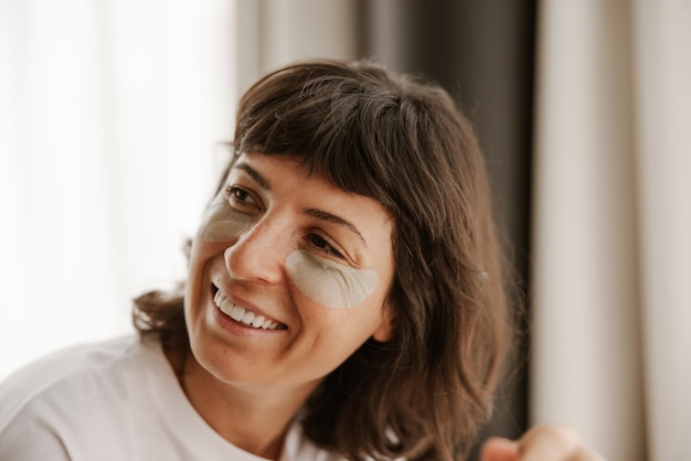 Vue rapprochée d'une femme fraîche regarde la caméra avec des patchs sourire