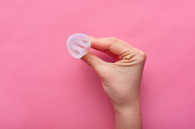 Vue rapprochée de femme tenant la coupe menstruelle isolé sur rose, période de la femme, coupe menstruelle dans les mains