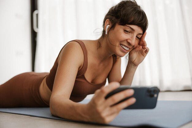 Vue rapprochée des femmes faisant du selfie sur un tapis de fitness à la maison