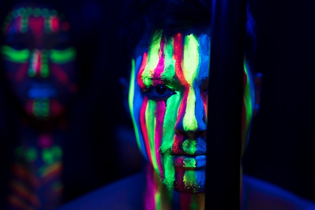 Vue rapprochée de l'homme avec du maquillage fluorescent et bâton