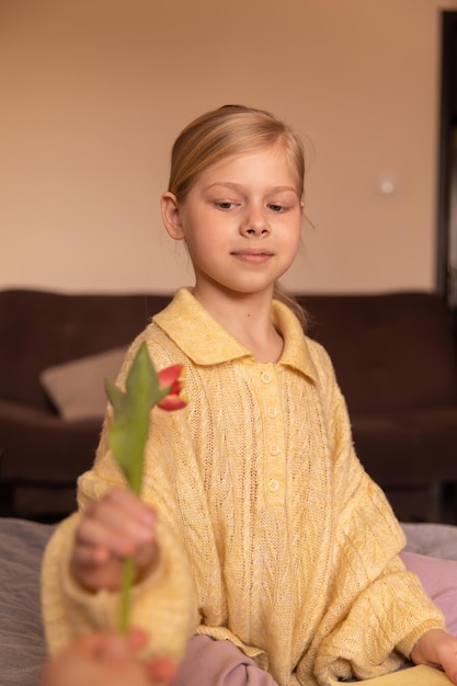 Vue rapprochée d'un jeune enfant souriant et mignon à la maison avec des fleurs