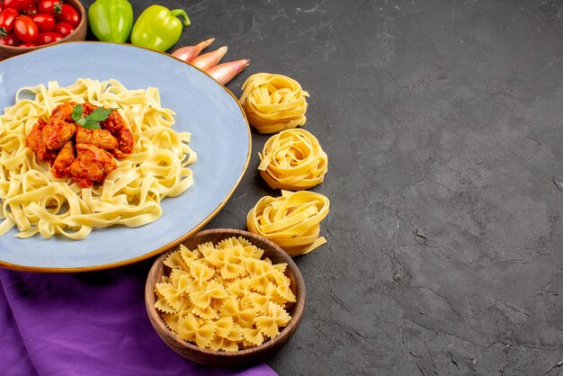 Vue rapprochée latérale assiette de nourriture boule d'oignon bol de poivrons de tomates à côté des pâtes et assiette de pâtes avec de la viande sur la nappe