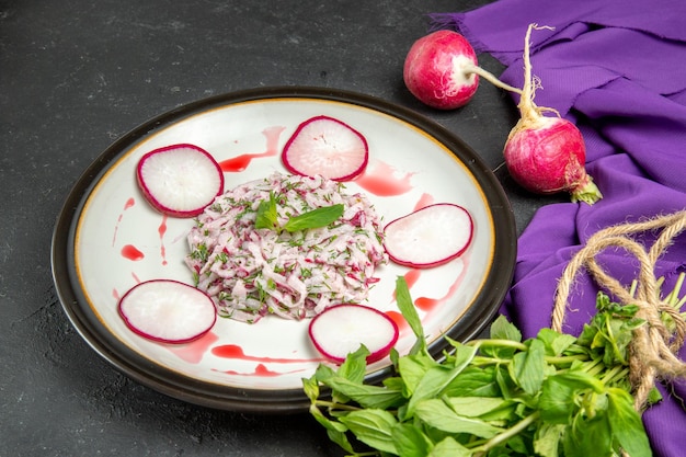 Vue rapprochée latérale d'une assiette de plat appétissant de radis et d'herbes en sauce et nappe violette