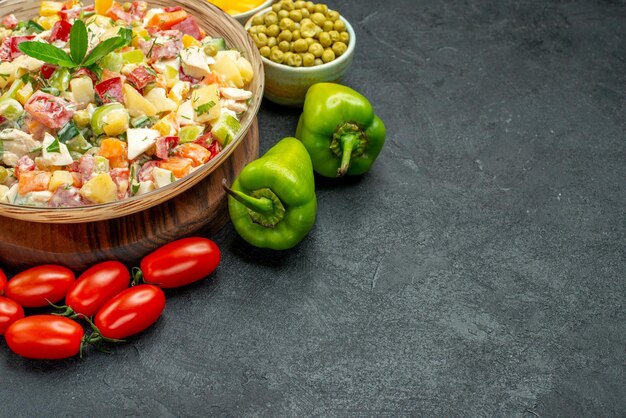 Vue rapprochée latérale d'un bol de salade de légumes avec des légumes sur le côté avec un espace libre pour votre texte sur fond gris foncé