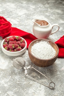 Vue rapprochée latérale du tamis à thé au chocolat à la farine et des baies sur le focus avec une serviette rouge sur le côté sur fond de marbre