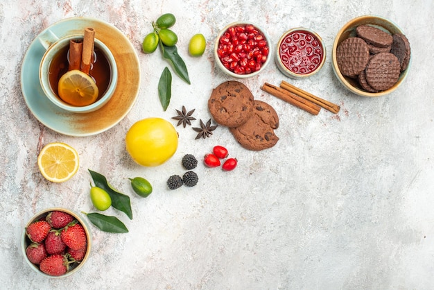 Vue rapprochée latérale du thé avec des biscuits aux baies la tasse de thé avec des fraises au citron agrumes sur la table