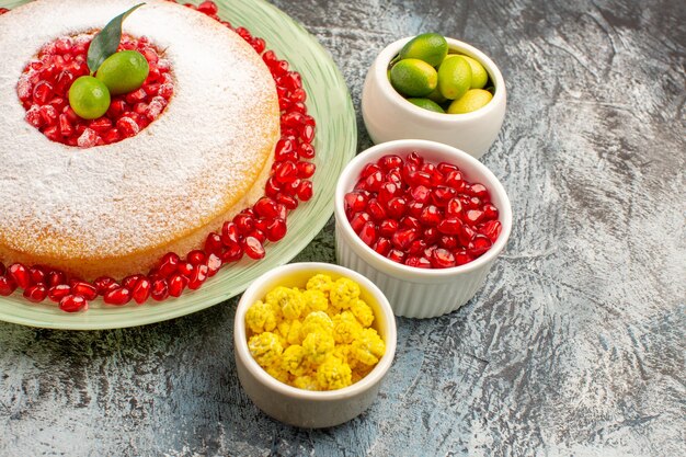 Vue rapprochée latérale un gâteau appétissant un gâteau appétissant bols de baies et trois grenades