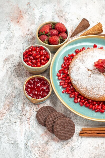 Vue rapprochée latérale le gâteau appétissant le gâteau appétissant à côté des bols de biscuits aux baies