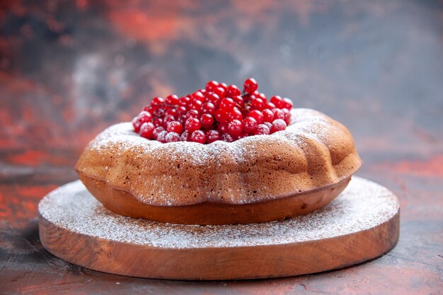 Vue rapprochée latérale d'un gâteau un gâteau appétissant avec des groseilles rouges sur la planche à découper