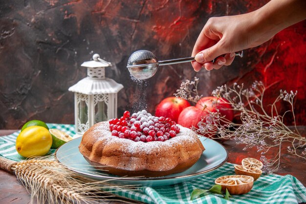 Vue rapprochée latérale un gâteau un gâteau avec des baies agrumes pommes cuillère à la main