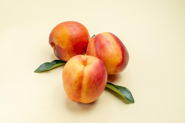 Vue rapprochée latérale nectarine trois nectarines appétissantes avec des feuilles sur la surface blanche