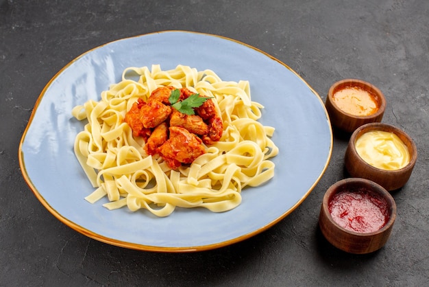 Vue Rapprochée Latérale Plat Appétissant Pâtes Viande Et Sauce Sur La Plaque Bleue à Côté Des Sauces Colorées Sur La Table