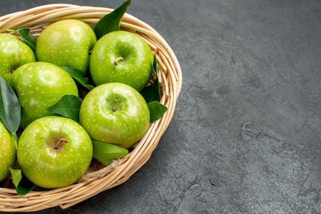 Vue rapprochée latérale des pommes dans le panier huit pommes avec des feuilles dans le panier en bois