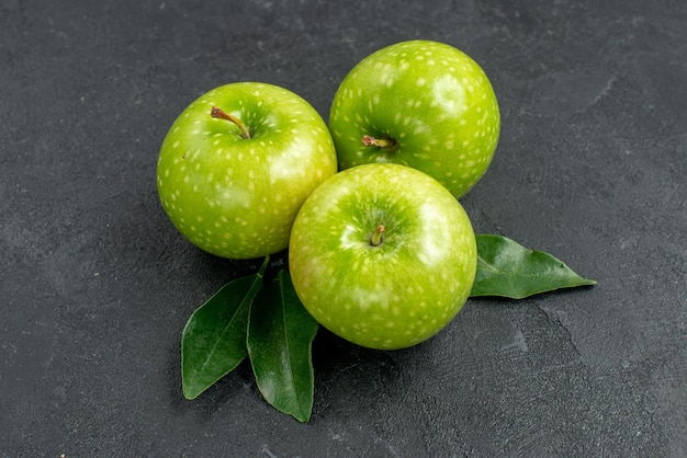 Vue rapprochée latérale des pommes vertes les pommes vertes appétissantes avec des feuilles sur la table sombre