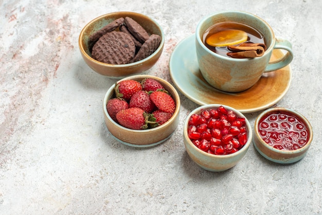 Vue Rapprochée Latérale Une Tasse De Thé Une Tasse De Thé Noir Avec Des Bols De Citron Et De Cannelle De Différents Biscuits Aux Baies Sur La Table