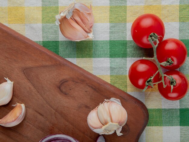 Vue rapprochée de légumes comme l'ail sur une surface en bois et la tomate sur une surface en tissu