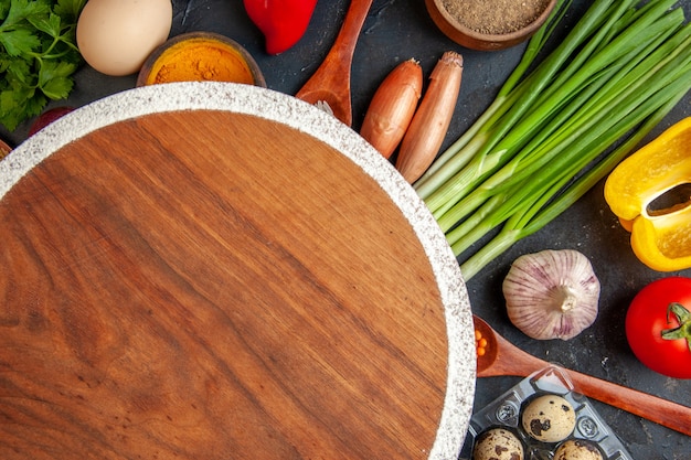 Vue rapprochée de légumes frais tombés bouteille d'huile sel poivre vert paquet autour d'une planche à découper sur dark