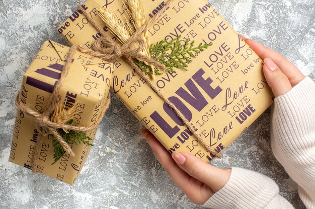 Vue rapprochée de la main tenant un beau cadeau emballé pour Noël sur la surface de la glace