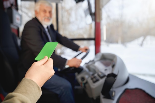 Photo gratuite vue rapprochée de la main tenant la carte de paiement verte montrant au conducteur lors de l'embarquement en public