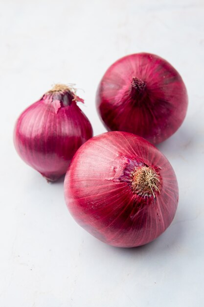 Vue rapprochée d'oignons rouges entiers sur fond blanc